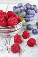 Glass bowls of raspberries and blueberries