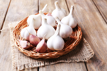 Fresh garlic on wicker mat, on wooden background