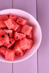 Slices of watermelon in pink plate on wooden background