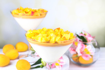 Apricot dessert in glasses on table on bright background