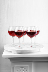 Glasses of wine on tray in room