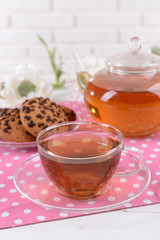 Teapot and cup of tea on table on brick wall background