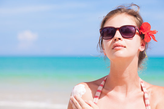 Portrait of Young woman in sunglasses putting sun cream on