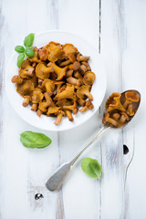 Plate with marinated chanterelles over white wooden background
