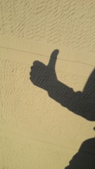 Thumbs up shadow on yellow wall