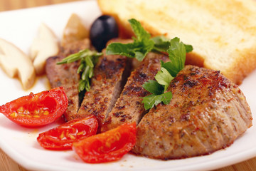 serving of meat with vegetables on a plate of white background