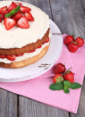 Delicious biscuit cake with strawberries on table close-up