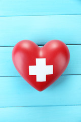 Red heart with cross sign on color wooden background