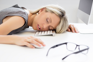 Fototapeta premium Exhausted woman sleeping in front of computer