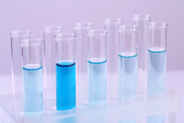 Test-tubes with blue liquid on lilac background