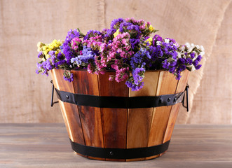 Big wooden basket with fresh flowers on sacking background