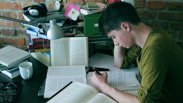 Student studying hard and reading books at home