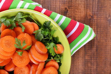 Slices of carrot, sorrel and parsley in green round bowl