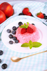 Round shaped cake with berries on plate on table cloth