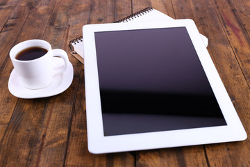 Fototapeta na wymiar Tablet, cup of coffee and notebook on wooden background