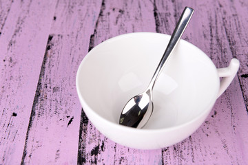 Empty cup with tea spoon on wooden background