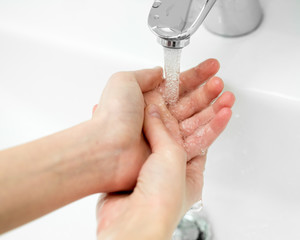Close-up of hands under stream of water from faucet