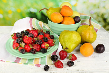 Ripe fruits and berries on table on bright background