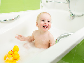 smiling toddler boy taking bath and playing with toys