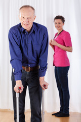 Physiotherapist and  man walking with crutches