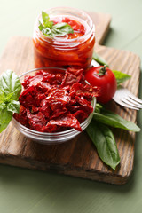 Sun dried tomatoes in glass jar, basil leaves