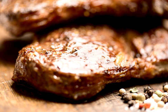 grilled steaks on an old wooden board macro