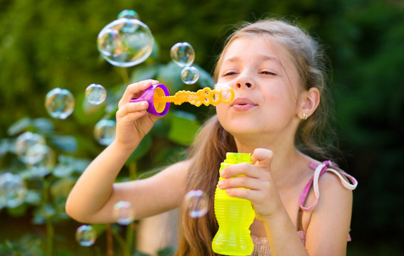 Little girl is blowing a soap bubbles