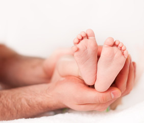 Obraz na płótnie Canvas Father holding his newborn baby's feet 