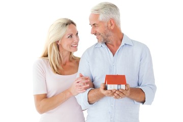 Happy couple holding miniature model house