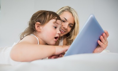Obraz premium Mother and daughter using digital tablet on bed