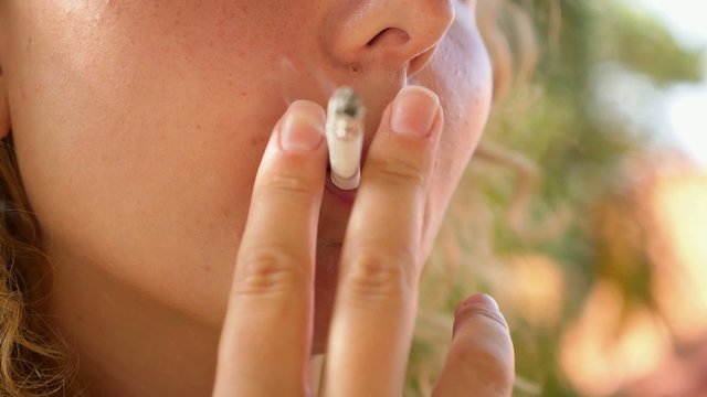 Smoking Young Woman. Closeup.