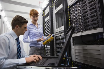 Team of technicians using digital cable analyser on servers
