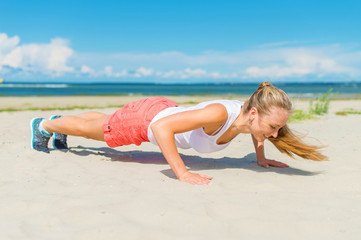 Woman doing push-ups on the beach.