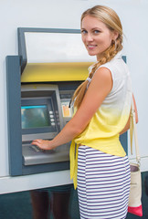 Pretty woman withdrawing money from an ATM.