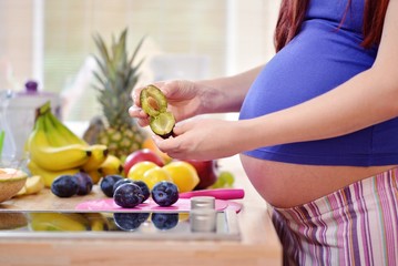pregnant woman holding a plum