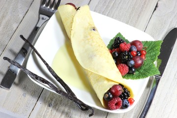 Pfannkuchen mit frischen Beeren auf Holztisch