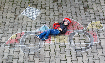 Little boy having fun with race car picture drawing with chalk