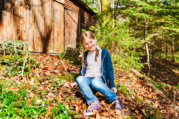 Autumn portrait of a cute little girl in forest on a sunny day