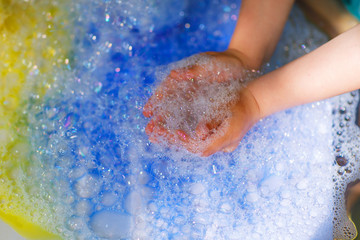 Hands of child playing with colorful soap bubbles.