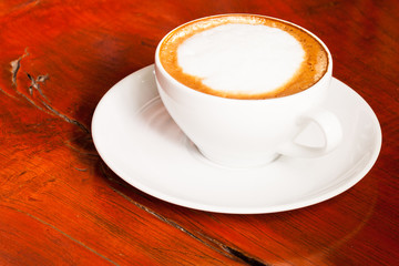 Cup of cappuccino or latte coffee on wood.