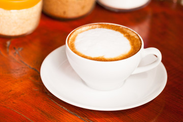 Cup of cappuccino or latte coffee on wood.