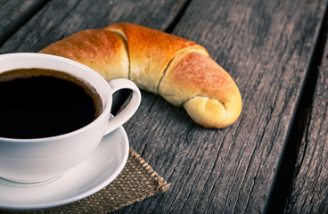 Coffee cup with a croissant breakfast