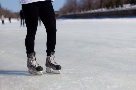 A pair of legs with ice skates on the ice during winter