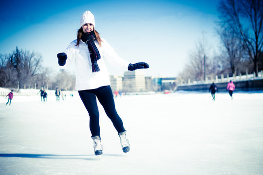 Attractive young woman ice skating during winter - blue filter a