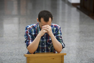 Handsome young man praying in a church