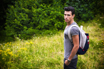 Handsome athletic young man with backpack at mountains