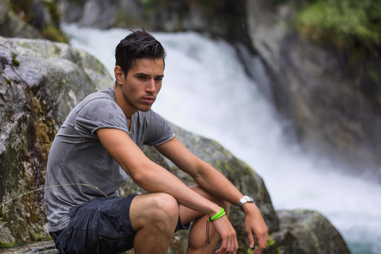 Handsome Young Man Near Mountain Waterfall On Rocks