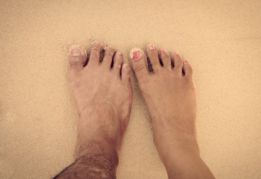 Feet Of Men And Women In The Sea Sand