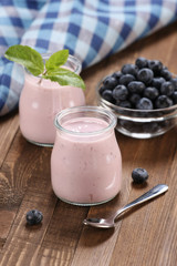 yogurt with blueberries in a glass jar and blueberries in a glas