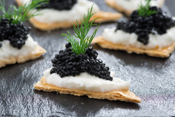 crackers with cream cheese and black caviar - obrazy, fototapety, plakaty